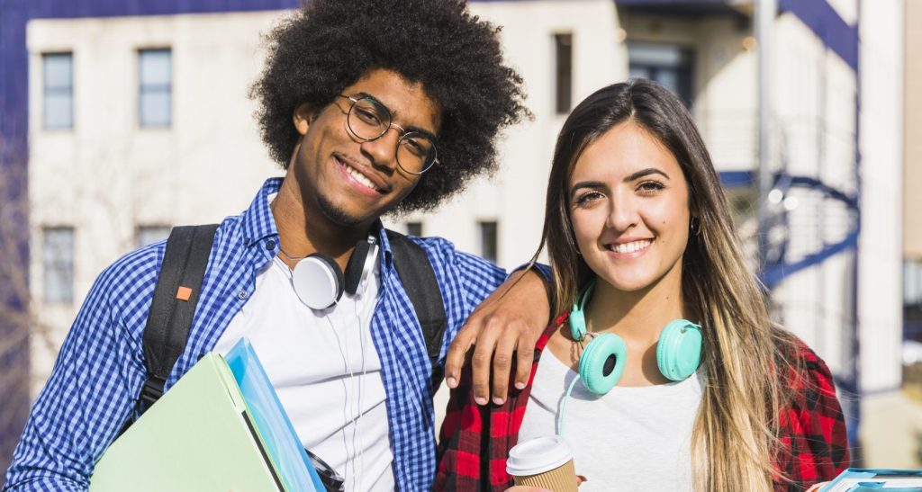casal-de-raca-mista-feliz-posando-em-frente-ao-predio-da-universidade – Copia